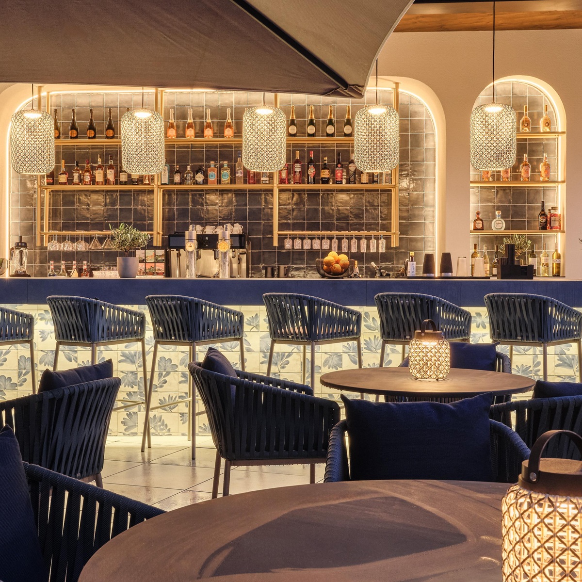 Stylische Poolbar mit moderner Theke, Sitzmöglichkeiten und auffälligen Hängeleuchten 